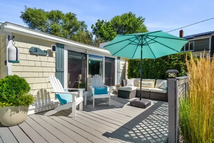 Front deck with outdoor couch, umbrella, and Adirondack chairs