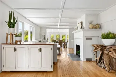 The coastal vibes in this home are next level. Walk through the living area to the dining area with seagrass chairs. The living room has a smart TV, the fireplace is inoperable. 
