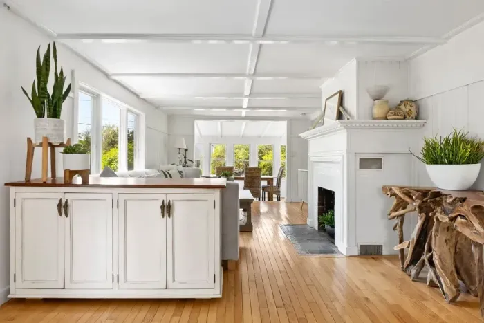 The coastal vibes in this home are next level. Walk through the living area to the dining area with seagrass chairs. The living room has a smart TV, the fireplace is inoperable. 