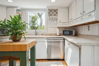 There is a dishwasher in this kitchen, plenty of plates, cups, utensils and more!