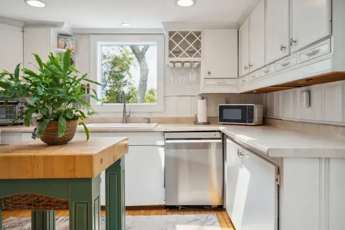 There is a dishwasher in this kitchen, plenty of plates, cups, utensils and more!
