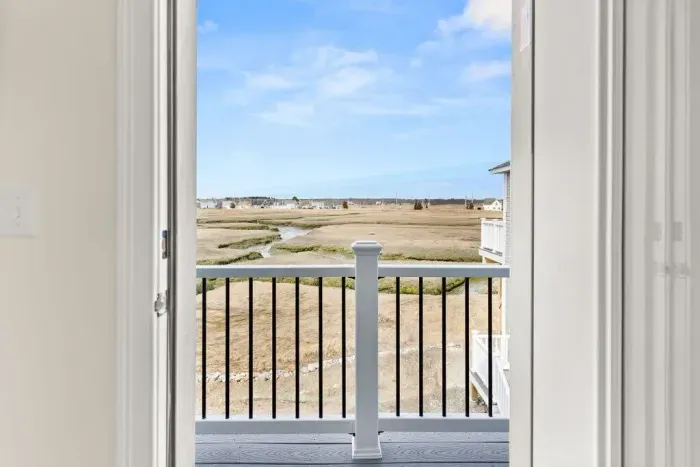 Small second floor balcony with 2-seater outdoor table. Featuring unobstructed views of the salt marsh