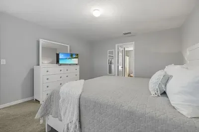 Primary bedroom with king bed, 2 walk-in closets, smart flatscreen TV and ensuite bathroom with tiled shower.
