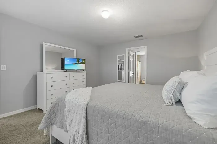 Primary bedroom with king bed, 2 walk-in closets, smart flatscreen TV and ensuite bathroom with tiled shower.