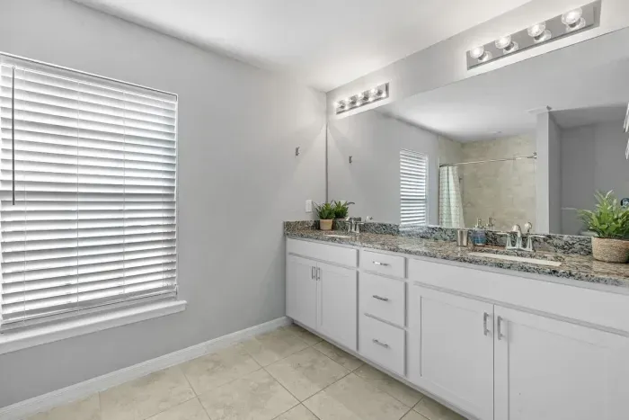 Primary bathroom with tiled shower and double vanity.