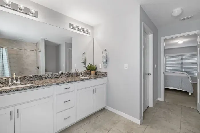 Primary bathroom with tiled shower and double vanity.