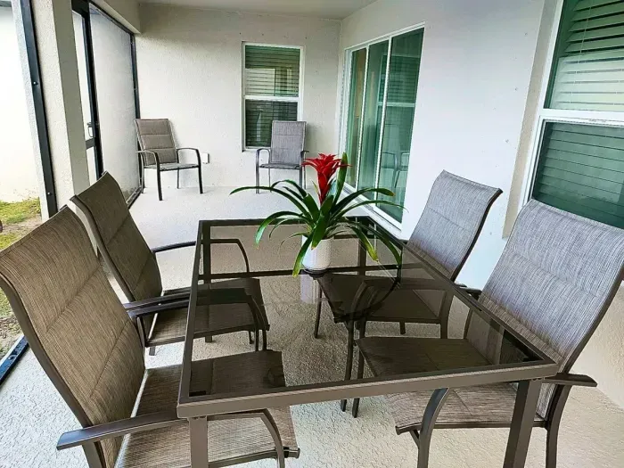 Outdoor screened-in lanai with dining table seating 6 people.