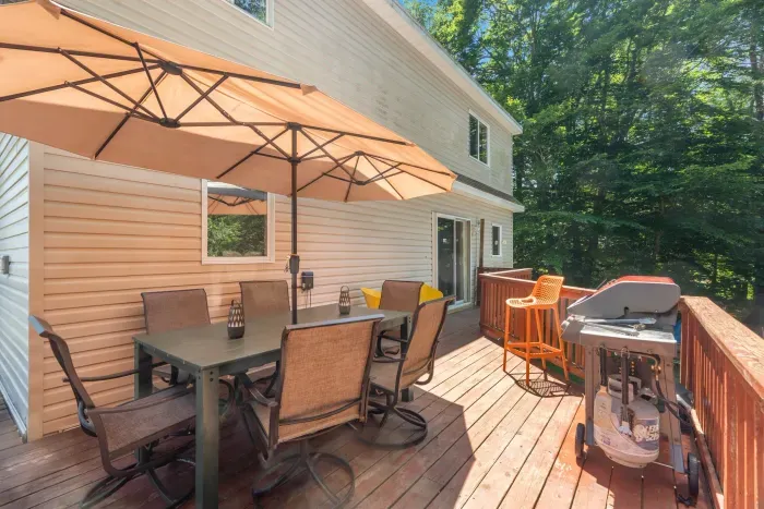 Spacious back deck with 6-person outdoor dining table, additional outdoor seating, and gas grill