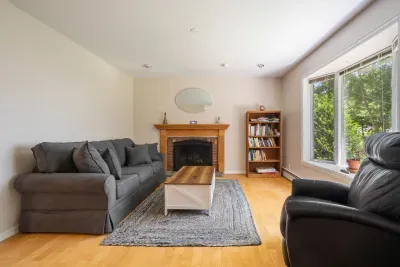 Den with full-sized sleeper sofa and recliner. Sleeper sofa looking out the widow at partial ocean views. Note - fireplace is inoperable
