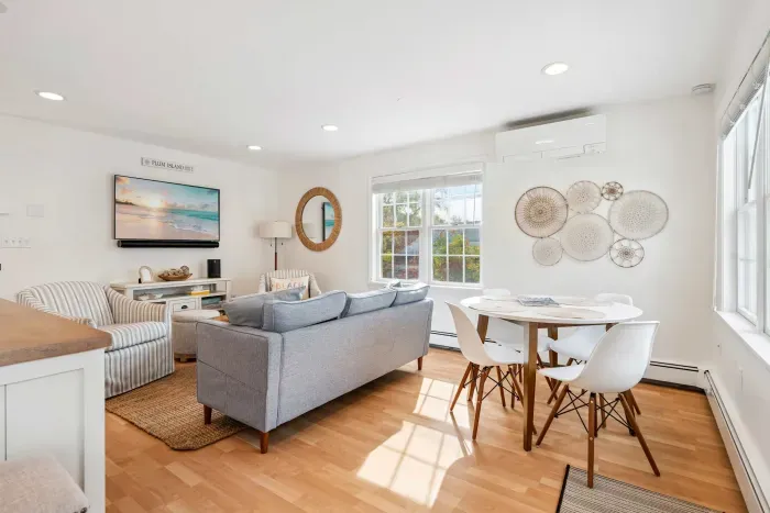 Living room with comfy couch, 2 chairs, and a large Smart TV