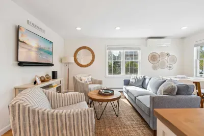 Living room with comfy couch, 2 chairs, and a large Smart TV