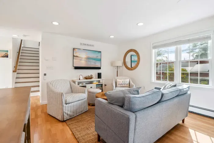 Living room with comfy couch, 2 chairs, and a large Smart TV