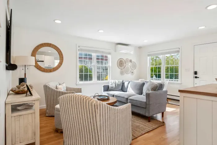 Living room with comfy couch, 2 chairs, and a large Smart TV
