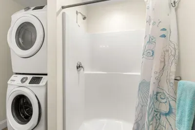 En-suite primary bathroom with double vanity sink, stand up shower and washer/dryer