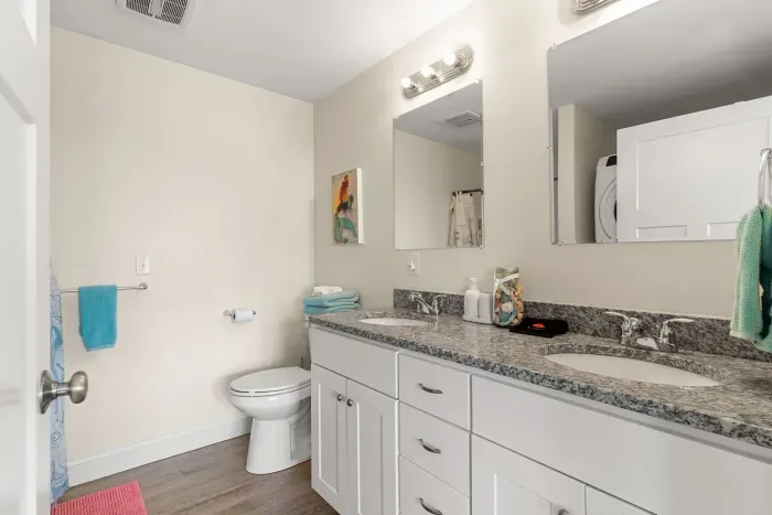 En-suite primary bathroom with double vanity sink, stand up shower and washer/dryer