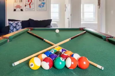 "The Game Room" features foosball, pool, wall-mounted connect 4, checkers, chess, dominoes, tic-tac-toe, a bar table with 3 stools, wall-mounted TV, slider leading to private balcony and a “work-from-home” desk