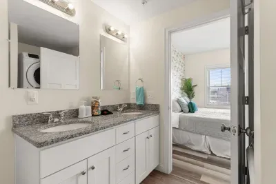 En-suite primary bathroom with double vanity sink, stand up shower and washer/dryer