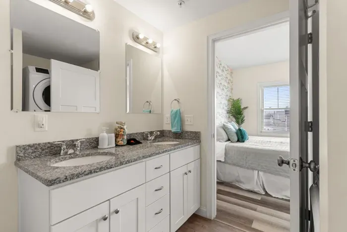 En-suite primary bathroom with double vanity sink, stand up shower and washer/dryer