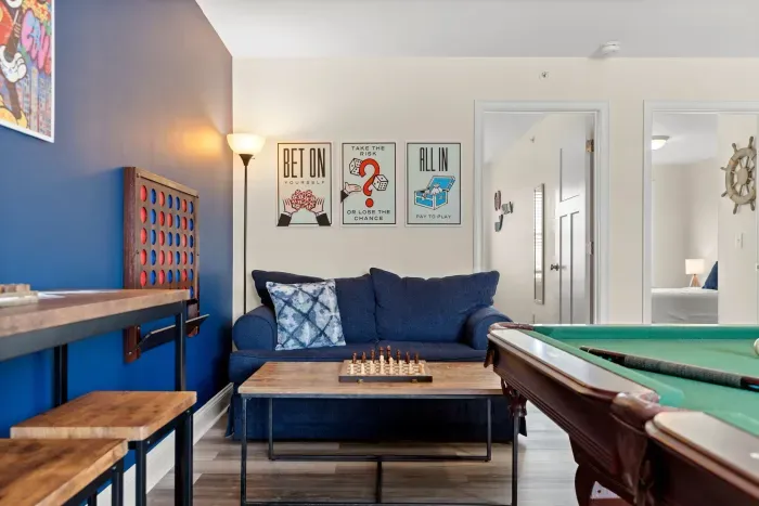 "The Game Room" features foosball, pool, wall-mounted connect 4, checkers, chess, dominoes, tic-tac-toe, a bar table with 3 stools, wall-mounted TV, slider leading to private balcony and a “work-from-home” desk