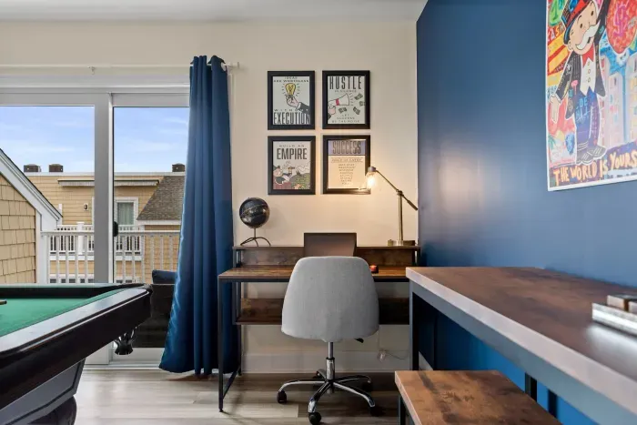 "The Game Room" features foosball, pool, wall-mounted connect 4, checkers, chess, dominoes, tic-tac-toe, a bar table with 3 stools, wall-mounted TV, slider leading to private balcony and a “work-from-home” desk