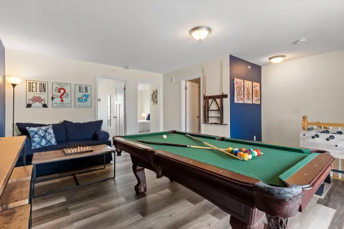 "The Game Room" features foosball, pool, wall-mounted connect 4, checkers, chess, dominoes, tic-tac-toe, a bar table with 3 stools, wall-mounted TV, slider leading to private balcony and a “work-from-home” desk