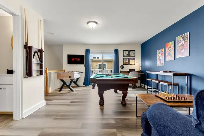 "The Game Room" features foosball, pool, wall-mounted connect 4, checkers, chess, dominoes, tic-tac-toe, a bar table with 3 stools, wall-mounted TV, slider leading to private balcony and a “work-from-home” desk
