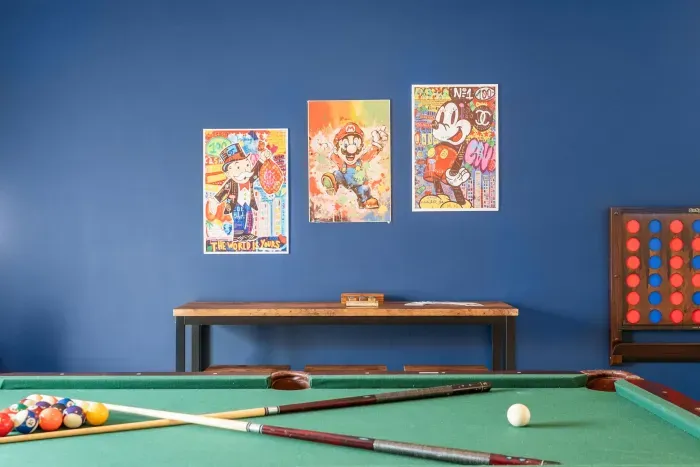 "The Game Room" features foosball, pool, wall-mounted connect 4, checkers, chess, dominoes, tic-tac-toe, a bar table with 3 stools, wall-mounted TV, slider leading to private balcony and a “work-from-home” desk