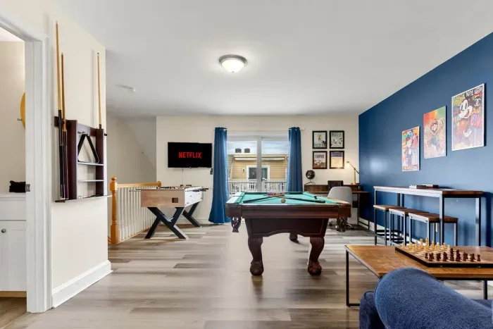 "The Game Room" features foosball, pool, wall-mounted connect 4, checkers, chess, dominoes, tic-tac-toe, a bar table with 3 stools, wall-mounted TV, slider leading to private balcony and a “work-from-home” desk