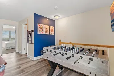 "The Game Room" features foosball, pool, wall-mounted connect 4, checkers, chess, dominoes, tic-tac-toe, a bar table with 3 stools, wall-mounted TV, slider leading to private balcony and a “work-from-home” desk