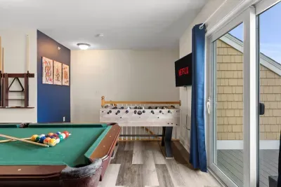 "The Game Room" features foosball, pool, wall-mounted connect 4, checkers, chess, dominoes, tic-tac-toe, a bar table with 3 stools, wall-mounted TV, slider leading to private balcony and a “work-from-home” desk
