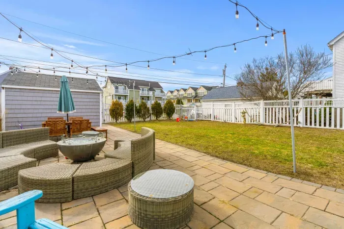 The shared backyard space features 2 grills, a shared propane fire pit, outdoor furniture, and string lights!