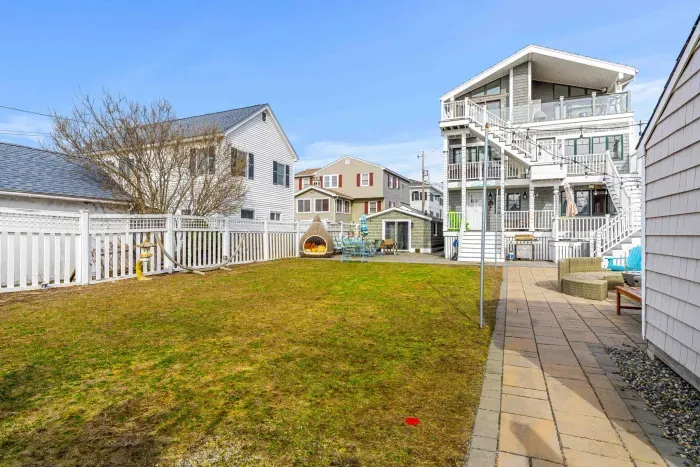 The shared backyard space features 2 grills, a shared propane fire pit, outdoor furniture, and string lights!