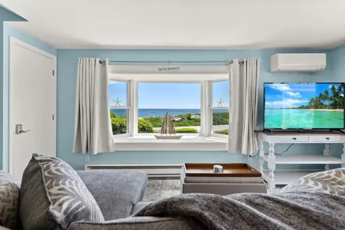 Open kitchen & living room with sleeper sofa, 50" smart TV, high-efficiency mini-split for AC/heat, and stunning views of the ocean.