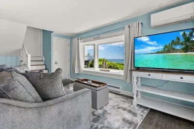 Open kitchen & living room with sleeper sofa, 50" smart TV, high-efficiency mini-split for AC/heat, and stunning views of the ocean.