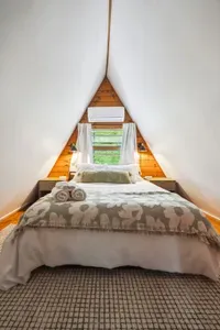 The primary bedroom! Featuring a subtle green theme, mini split heating and cooling, queen bed, 100% cotton bedding, and blackout curtains. Please note there is no overhead lighting in this room. Clean linens provided.