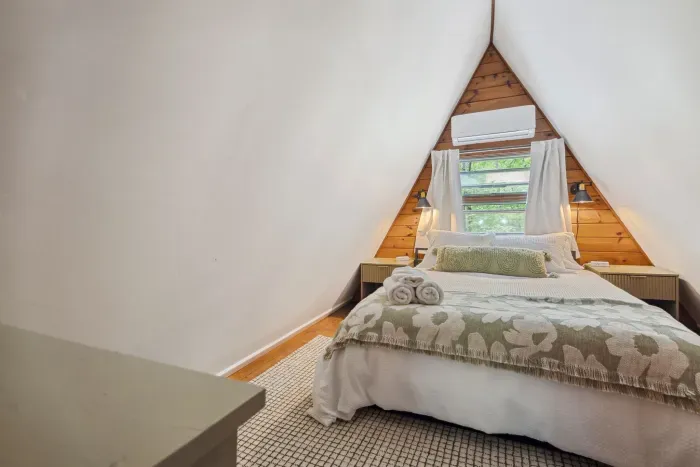 The primary bedroom! Featuring a subtle green theme, mini split heating and cooling, queen bed, 100% cotton bedding, and blackout curtains. Please note: there is no overhead lighting in this room. Clean linens provided.