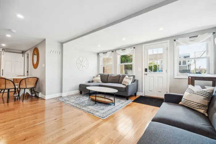 Spacious living room with smart TV, sectional couch, standard couch, and hightop table for added workspace or dining