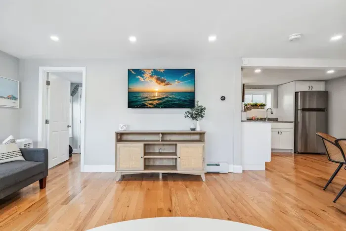 Spacious living room with smart TV, sectional couch, standard couch, and hightop table for added workspace or dining