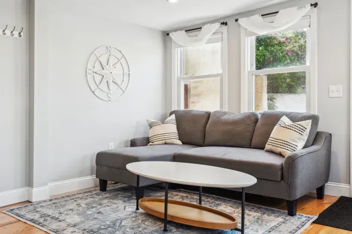 Spacious living room with smart TV, sectional couch, standard couch, and hightop table for added workspace or dining