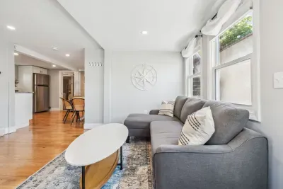 Spacious living room with smart TV, sectional couch, standard couch, and hightop table for added workspace or dining