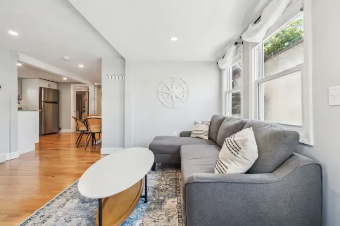 Spacious living room with smart TV, sectional couch, standard couch, and hightop table for added workspace or dining