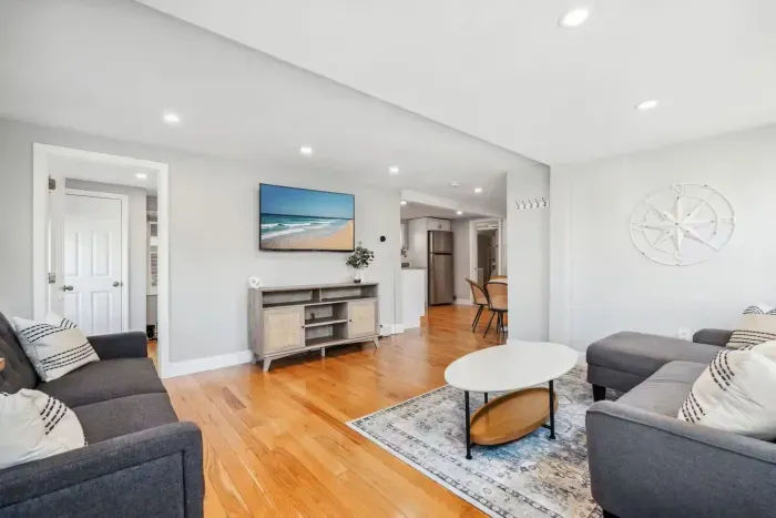 Spacious living room with smart TV, sectional couch, standard couch, and hightop table for added workspace or dining