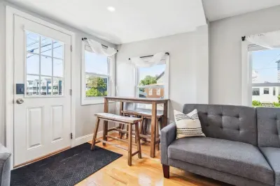Spacious living room with smart TV, sectional couch, standard couch, and hightop table for added workspace or dining