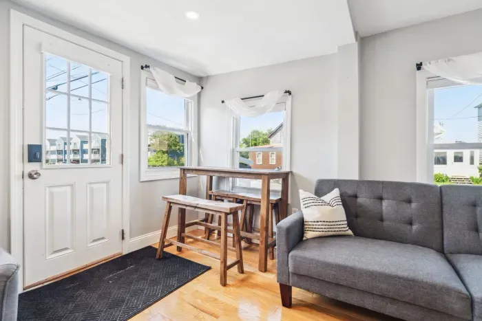 Spacious living room with smart TV, sectional couch, standard couch, and hightop table for added workspace or dining