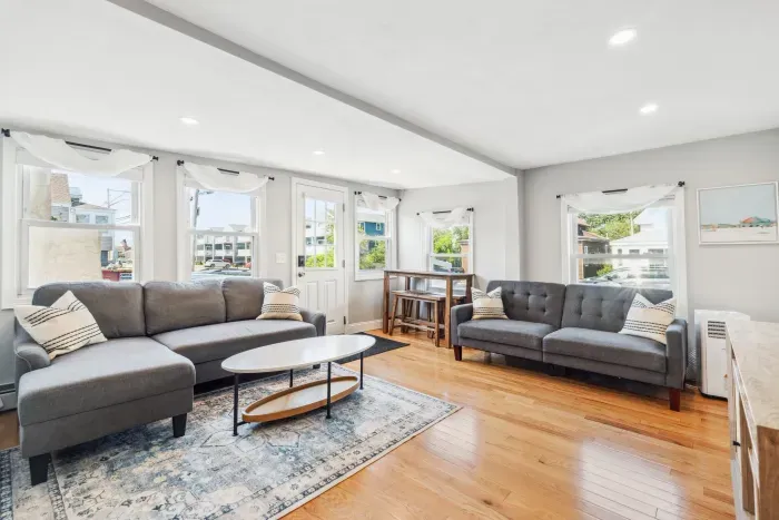 Spacious living room with smart TV, sectional couch, standard couch, and hightop table for added workspace or dining