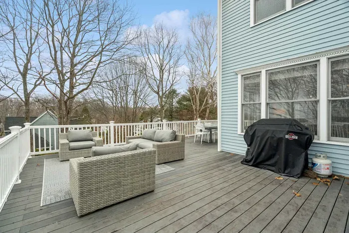 Expansive rear deck with gray wicker lounge seating, a dining area, a gas grill, and views of the water! There's an outdoor shower located off the deck also!