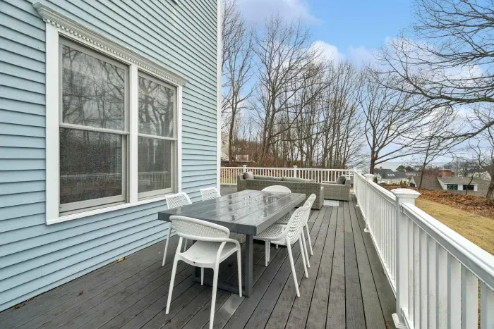 Expansive rear deck with gray wicker lounge seating, a dining area, a gas grill, and views of the water! There's an outdoor shower located off the deck also!