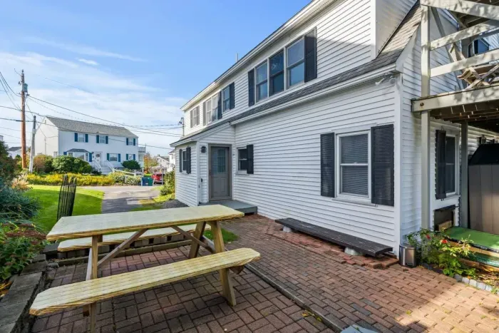 Patio in side yard with outdoor grill and picnic table.