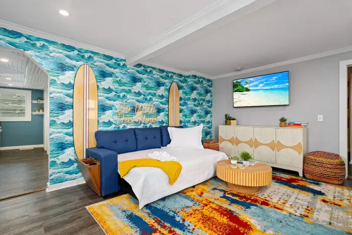 Living Room with "go with the flow" neon light sign, flat screen smart TV and sleeper sofa