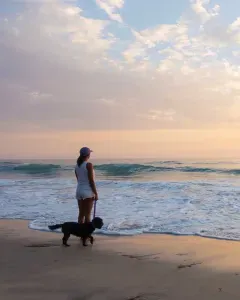 Woman walking her dog on a New Hampshire pet-friendly beach at sunset